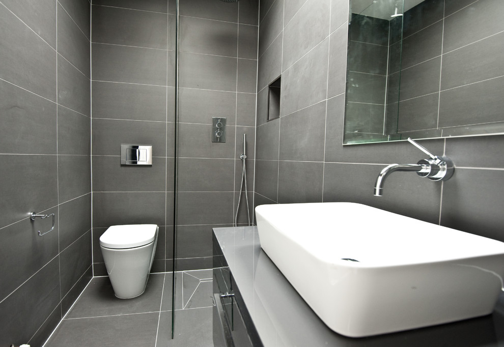 Пример оригинального дизайна: маленькая главная ванная комната в современном стиле с плоскими фасадами, серыми фасадами, открытым душем, унитазом-моноблоком, серой плиткой, керамической плиткой, серыми стенами, полом из керамической плитки и раковиной с несколькими смесителями для на участке и в саду