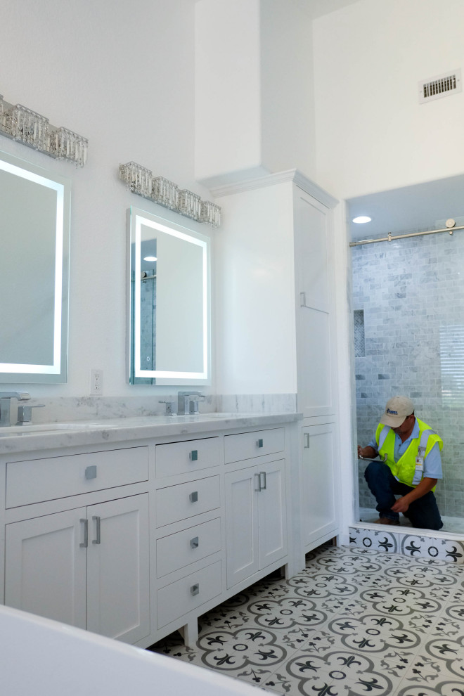 Свежая идея для дизайна: главная ванная комната среднего размера в современном стиле с плоскими фасадами, белыми фасадами, отдельно стоящей ванной, душем в нише, унитазом-моноблоком, белой плиткой, мраморной плиткой, белыми стенами, полом из мозаичной плитки, врезной раковиной, столешницей из искусственного кварца, серым полом, душем с раздвижными дверями, белой столешницей, тумбой под две раковины и напольной тумбой - отличное фото интерьера