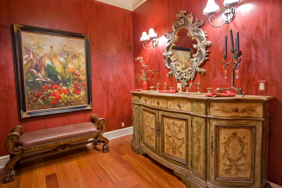 Réalisation d'une salle de bain tradition avec un lavabo posé, un mur rouge et un placard avec porte à panneau encastré.