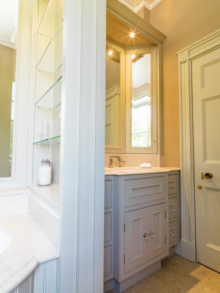 На фото: главная ванная комната среднего размера в классическом стиле с накладной раковиной, фасадами с выступающей филенкой, зелеными фасадами, столешницей из известняка, накладной ванной, унитазом-моноблоком, коричневыми стенами и полом из известняка