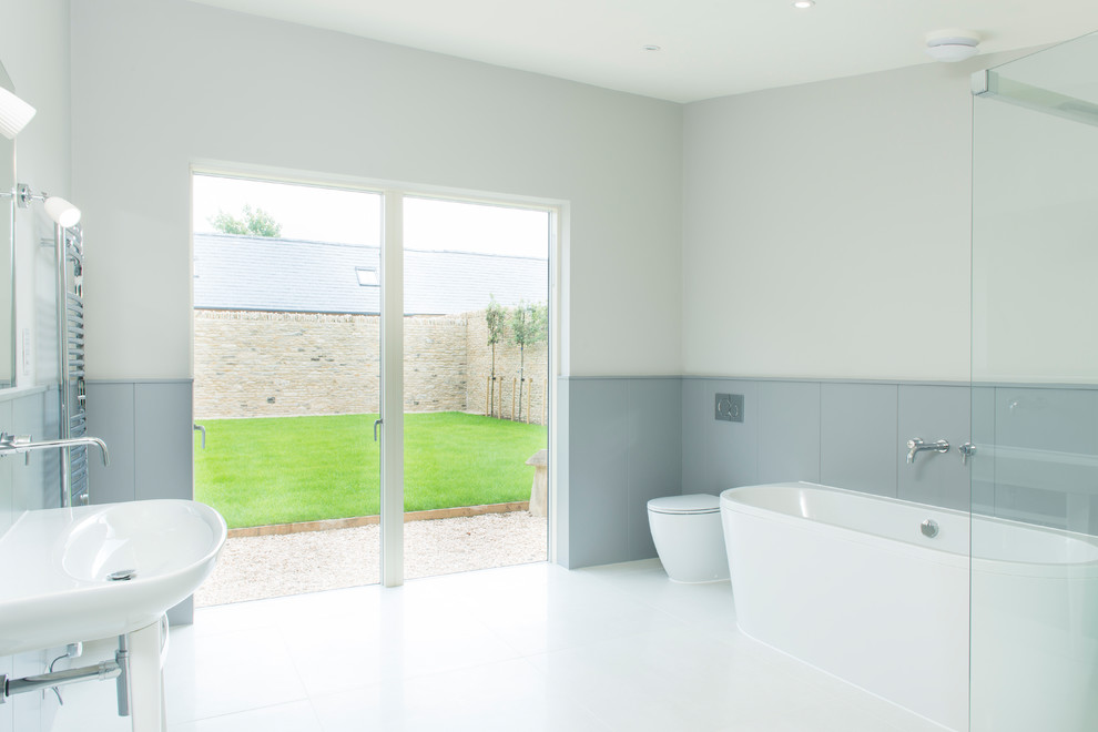 Exempel på ett lantligt en-suite badrum, med en toalettstol med hel cisternkåpa, grå kakel, grå väggar, ett piedestal handfat, vitt golv, dusch med gångjärnsdörr och ett fristående badkar