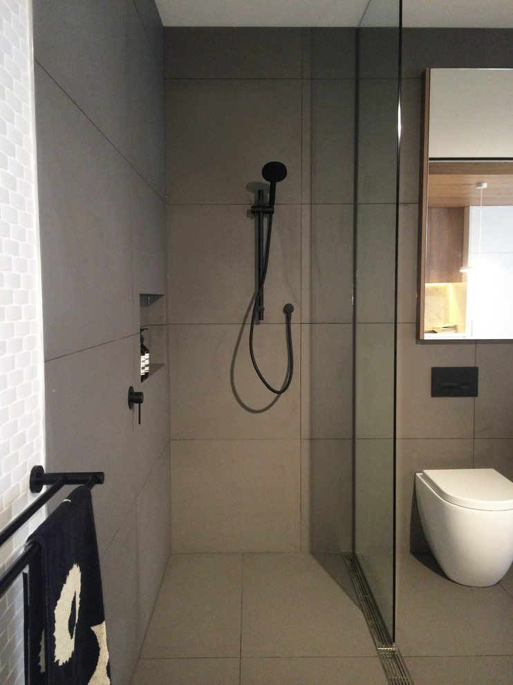 Immagine di una piccola stanza da bagno padronale minimalista con doccia aperta, WC sospeso, piastrelle grigie, piastrelle in pietra e pareti grigie