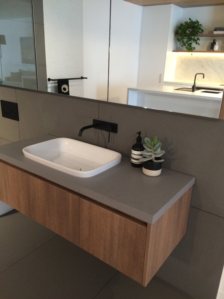 Design ideas for a small modern ensuite bathroom in Melbourne with a built-in sink, flat-panel cabinets, medium wood cabinets, solid surface worktops, grey tiles, stone tiles and grey walls.