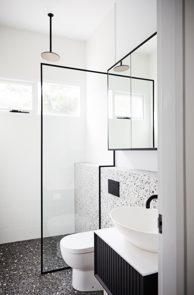 Пример оригинального дизайна: маленькая детская ванная комната в современном стиле с фасадами островного типа, черными фасадами, открытым душем, унитазом-моноблоком, черно-белой плиткой, керамической плиткой, белыми стенами, бетонным полом, настольной раковиной, столешницей из искусственного камня, черным полом, открытым душем, белой столешницей, нишей, тумбой под одну раковину и подвесной тумбой для на участке и в саду