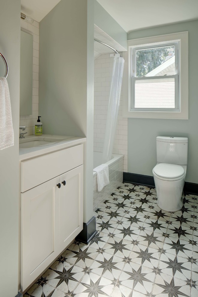 Design ideas for a small classic bathroom in New York with shaker cabinets, white cabinets, an alcove bath, a shower/bath combination, a two-piece toilet, white tiles, ceramic tiles, blue walls, porcelain flooring, a submerged sink, engineered stone worktops, multi-coloured floors and white worktops.