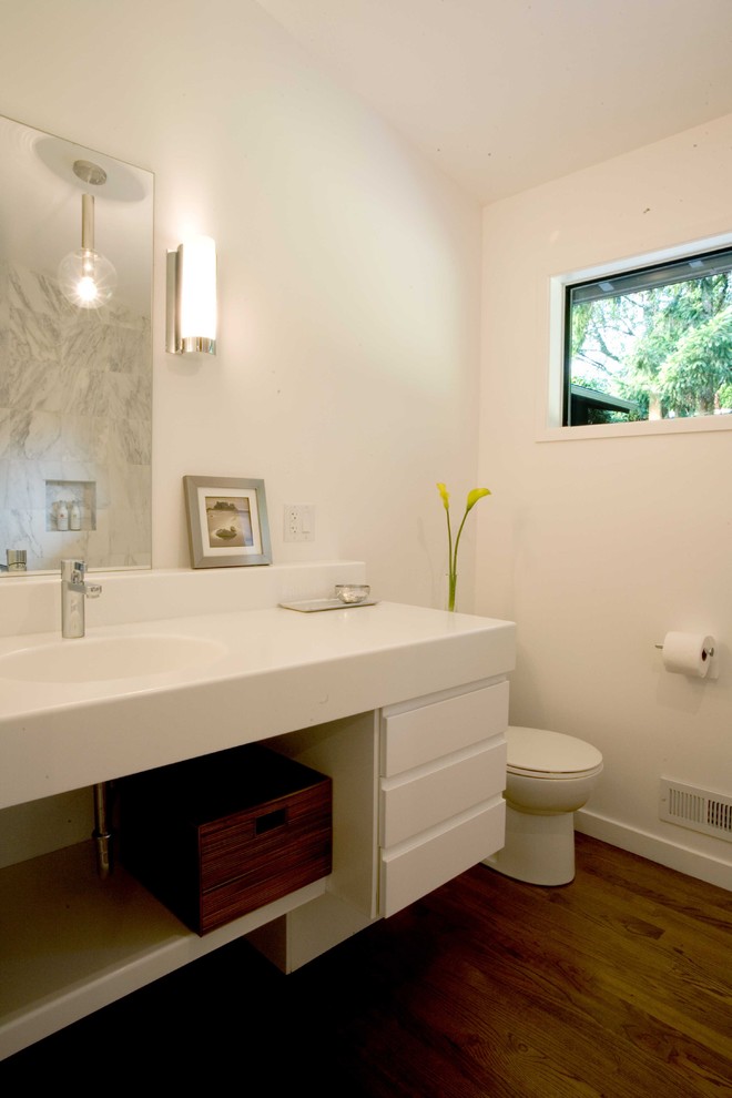 Bild på ett funkis badrum, med ett integrerad handfat, öppna hyllor och vita skåp
