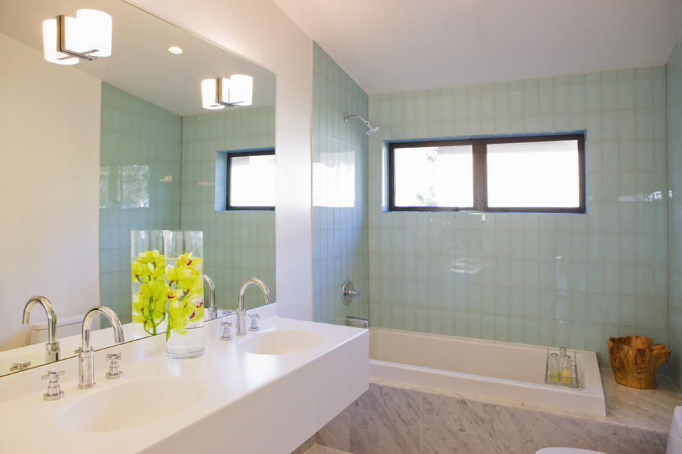 ポートランドにあるモダンスタイルのおしゃれな浴室 (一体型シンク、ドロップイン型浴槽、シャワー付き浴槽	、青いタイル、ガラスタイル、照明) の写真