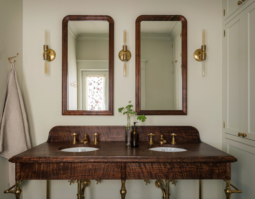 Foto di una stanza da bagno chic con ante in legno bruno, pareti bianche, lavabo sottopiano e top in legno