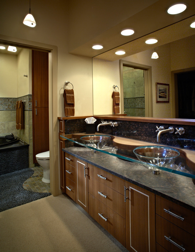 На фото: главная ванная комната среднего размера в современном стиле с темными деревянными фасадами, стеклянной столешницей, унитазом-моноблоком, бежевыми стенами и полом из галечной плитки