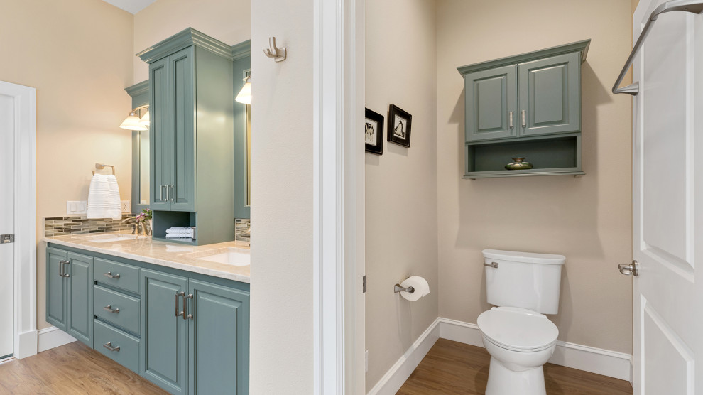 他の地域にあるお手頃価格の中くらいなトラディショナルスタイルのおしゃれなマスターバスルーム (レイズドパネル扉のキャビネット、緑のキャビネット、ドロップイン型浴槽、ベージュのタイル、ベージュの壁、アンダーカウンター洗面器、珪岩の洗面台、茶色い床、開き戸のシャワー、ベージュのカウンター、トイレ室、洗面台2つ、造り付け洗面台) の写真