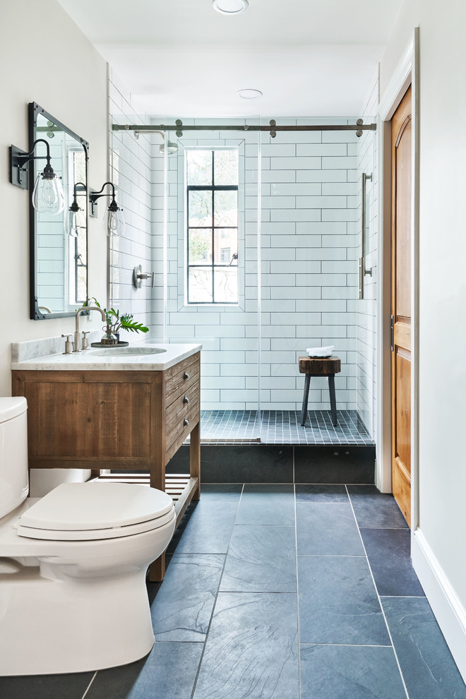 Cette image montre une salle d'eau méditerranéenne en bois brun avec une douche d'angle, WC à poser, un carrelage blanc, un mur beige, un lavabo encastré, un sol bleu, une cabine de douche à porte coulissante, un plan de toilette blanc et un placard à porte plane.