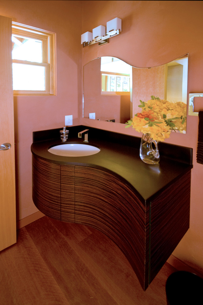 Foto di una stanza da bagno contemporanea di medie dimensioni con ante lisce, ante in legno bruno, WC a due pezzi, pareti rosse, parquet scuro, lavabo sottopiano e pavimento marrone