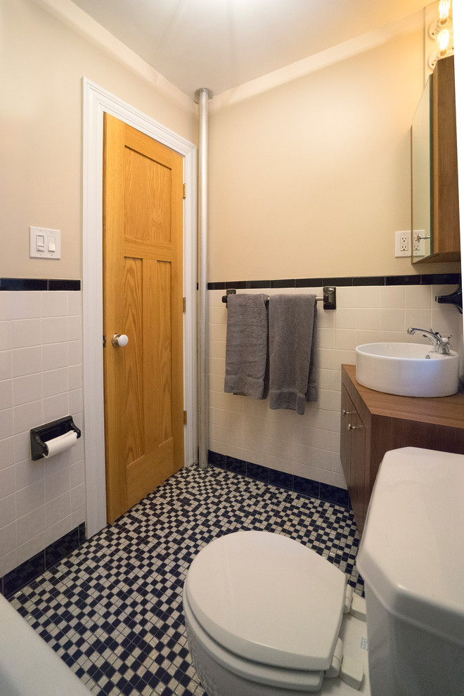 This is an example of a small contemporary bathroom in New York with a vessel sink, freestanding cabinets, medium wood cabinets, an alcove bath, a two-piece toilet, white tiles, ceramic tiles, beige walls and mosaic tile flooring.