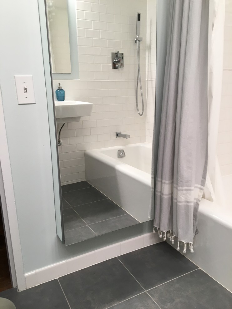 Modern inredning av ett litet badrum, med ett badkar i en alkov, en dusch i en alkov, en toalettstol med hel cisternkåpa, vit kakel, keramikplattor, blå väggar, klinkergolv i porslin, ett väggmonterat handfat, blått golv och dusch med duschdraperi