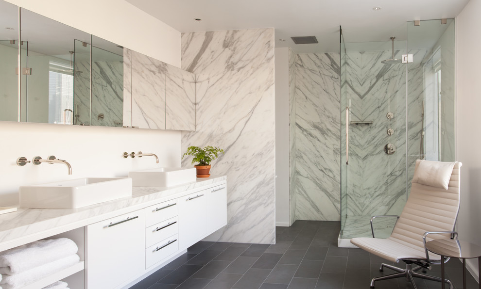 Modernes Badezimmer mit Aufsatzwaschbecken, flächenbündigen Schrankfronten, weißen Schränken, Duschnische, weißen Fliesen, Steinplatten und weißer Wandfarbe in New York