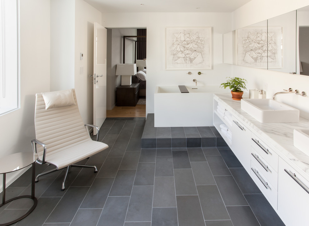 Diseño de cuarto de baño contemporáneo con lavabo sobreencimera, armarios con paneles lisos, puertas de armario blancas, bañera exenta y paredes blancas