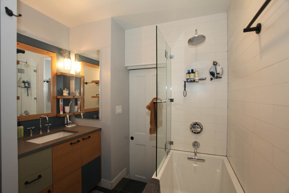 Exemple d'une petite salle de bain principale tendance en bois clair avec un placard à porte plane, un combiné douche/baignoire, un carrelage blanc, un mur gris, une baignoire en alcôve, WC à poser, des carreaux de céramique, un sol en ardoise, un lavabo encastré et un plan de toilette en quartz modifié.
