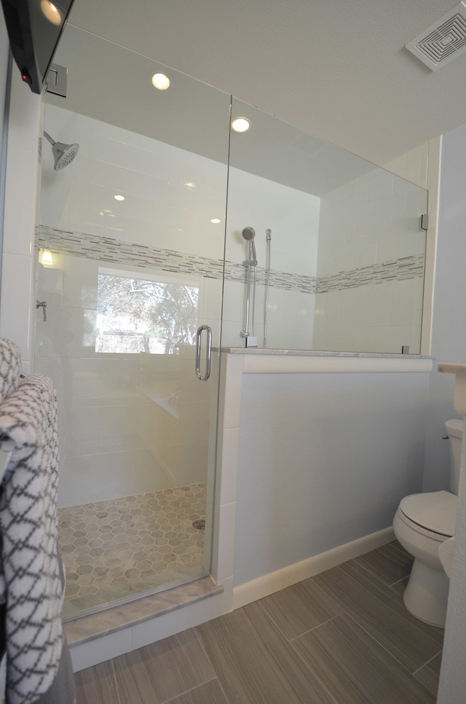 Modelo de cuarto de baño contemporáneo de tamaño medio con lavabo bajoencimera, armarios con paneles lisos, puertas de armario blancas, encimera de mármol, bañera encastrada, baldosas y/o azulejos blancos, paredes azules y suelo de baldosas de porcelana