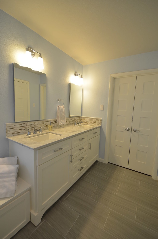Idées déco pour une salle de bain contemporaine avec un lavabo encastré, un placard à porte plane, des portes de placard blanches, un plan de toilette en marbre, une baignoire posée, un carrelage blanc, un mur bleu et un sol en carrelage de porcelaine.