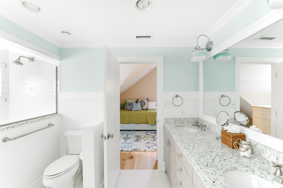 Bild på ett maritimt badrum för barn, med ett undermonterad handfat, skåp i ljust trä, bänkskiva i återvunnet glas, en toalettstol med separat cisternkåpa, keramikplattor, blå väggar och klinkergolv i keramik