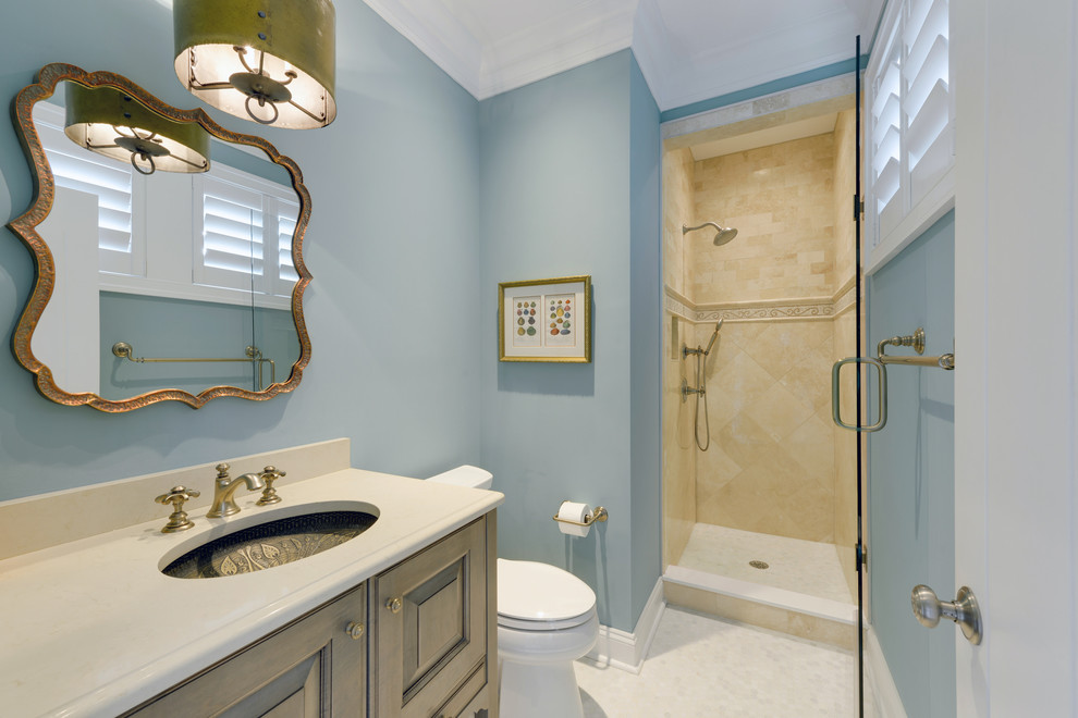 Пример оригинального дизайна: ванная комната в морском стиле с врезной раковиной, фасадами с выступающей филенкой, светлыми деревянными фасадами, столешницей из искусственного кварца, унитазом-моноблоком, бежевой плиткой, каменной плиткой, синими стенами и мраморным полом
