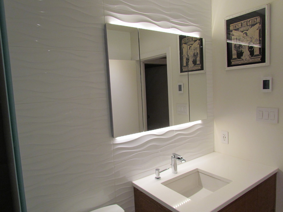 Kleines Modernes Duschbad mit flächenbündigen Schrankfronten, weißen Fliesen, Porzellanfliesen, weißer Wandfarbe, dunklen Holzschränken, Wandwaschbecken, Mineralwerkstoff-Waschtisch und Wandtoilette mit Spülkasten in Vancouver