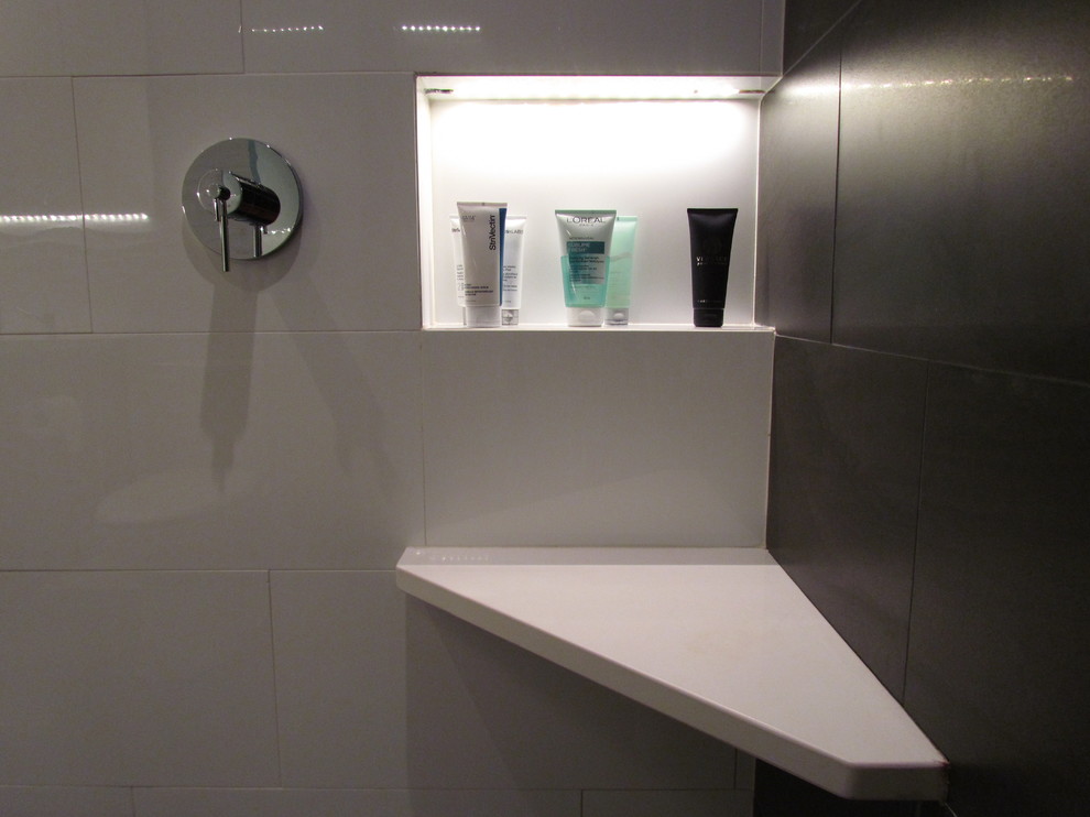 Idéer för att renovera ett litet funkis badrum med dusch, med släta luckor, vit kakel, porslinskakel, vita väggar, skåp i mörkt trä, en toalettstol med separat cisternkåpa, ett väggmonterat handfat och bänkskiva i akrylsten