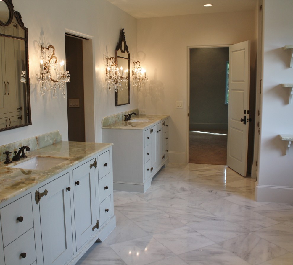 Exemple d'une grande salle de bain principale montagne avec un lavabo encastré, un placard à porte shaker, des portes de placard blanches, un plan de toilette en marbre, un carrelage beige, des dalles de pierre, un mur beige et un sol en marbre.