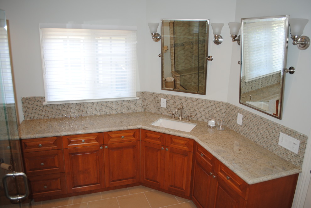 Immagine di una stanza da bagno classica con lavabo sottopiano, ante con bugna sagomata, ante in legno scuro, top in granito, doccia alcova, WC a due pezzi e piastrelle beige