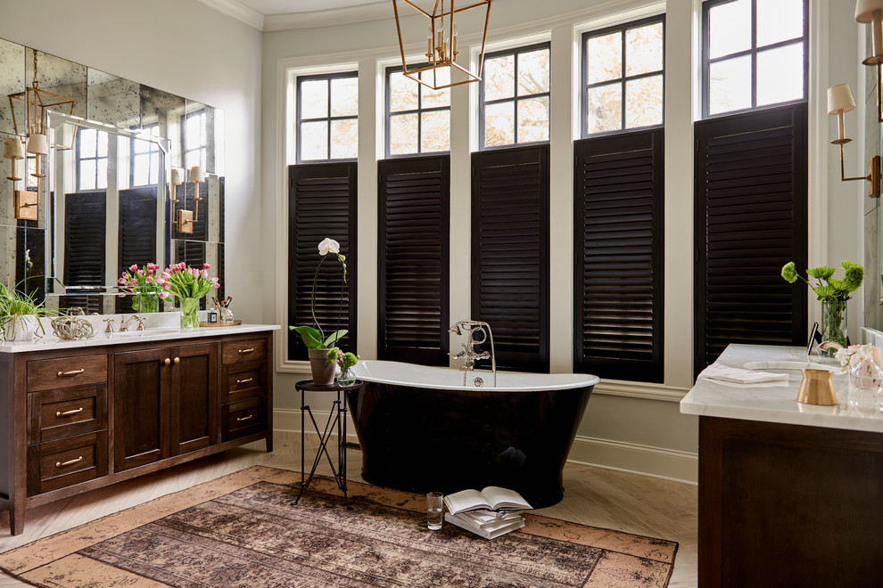 Inspiration for a traditional ensuite bathroom in Other with shaker cabinets, dark wood cabinets, a freestanding bath, grey walls, a submerged sink and beige floors.