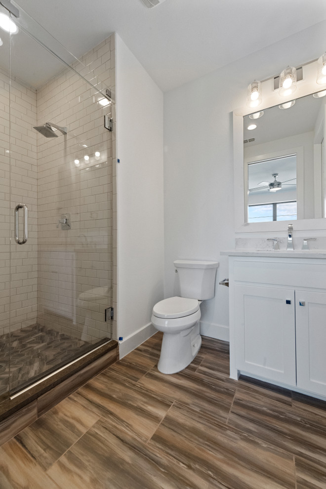 Источник вдохновения для домашнего уюта: маленькая ванная комната в современном стиле с фасадами с утопленной филенкой, белыми фасадами, душем в нише, унитазом-моноблоком, белой плиткой, плиткой кабанчик, белыми стенами, полом из керамической плитки, душевой кабиной, врезной раковиной, столешницей из кварцита, коричневым полом, душем с распашными дверями, белой столешницей, тумбой под одну раковину и встроенной тумбой для на участке и в саду