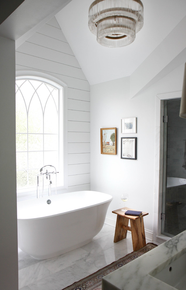 Réalisation d'une salle de bain principale champêtre avec un mur blanc, un sol en marbre, un plan de toilette en marbre et une baignoire indépendante.