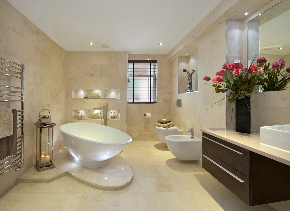 Idée de décoration pour une grande salle de bain design en bois foncé avec un placard à porte plane, une baignoire indépendante, WC suspendus, des carreaux de porcelaine, un sol en carrelage de porcelaine, une vasque, un carrelage beige et un mur beige.