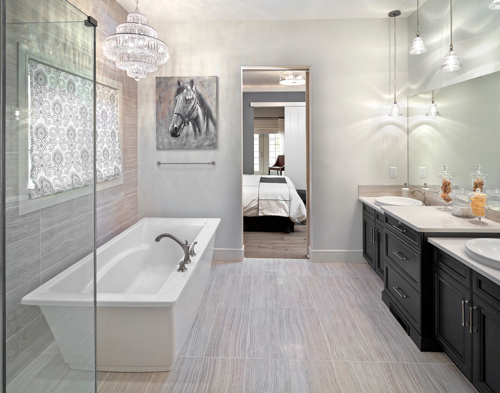 Ispirazione per una stanza da bagno tradizionale con lavabo a bacinella, ante con riquadro incassato, ante nere, vasca freestanding e piastrelle beige