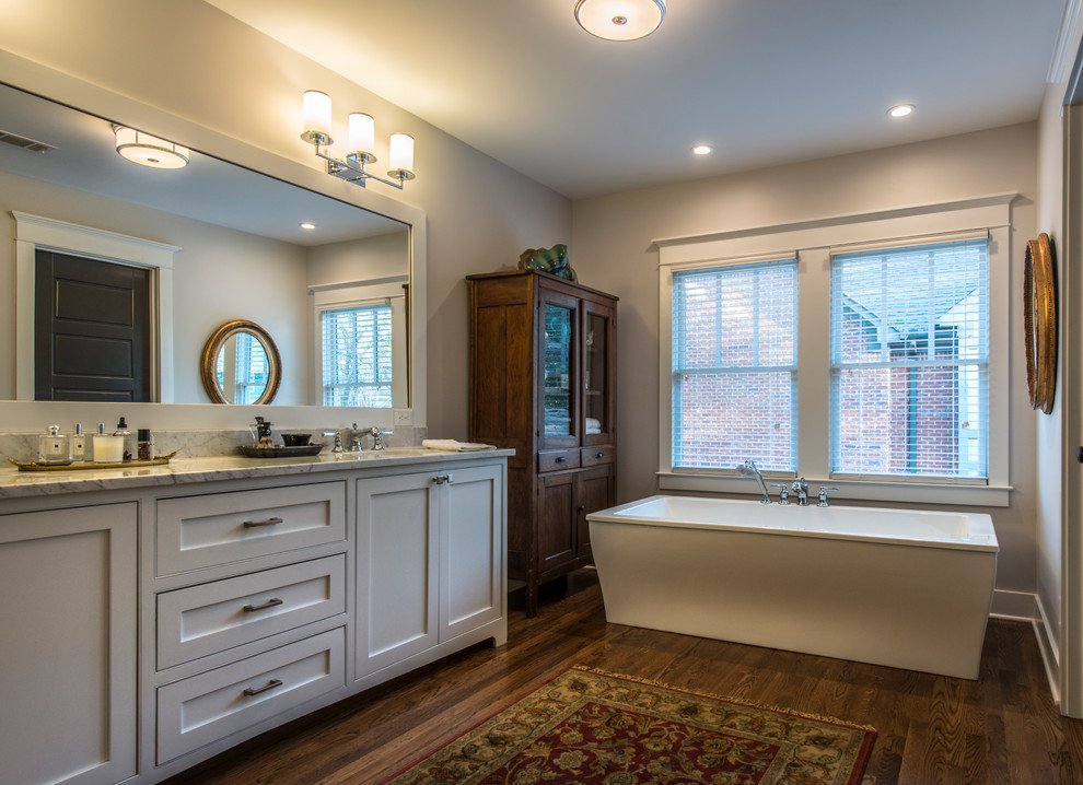 Idéer för ett mellanstort klassiskt en-suite badrum, med skåp i shakerstil, vita skåp, ett fristående badkar, en toalettstol med hel cisternkåpa, grå väggar, mellanmörkt trägolv, ett undermonterad handfat och granitbänkskiva