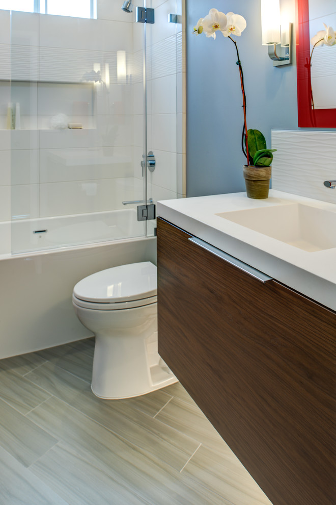 Cette image montre une petite salle de bain asiatique en bois brun avec un placard à porte plane, une baignoire en alcôve, un combiné douche/baignoire, WC séparés, un carrelage blanc, des carreaux de porcelaine, un mur gris, un sol en carrelage de porcelaine, un lavabo intégré, un plan de toilette en surface solide, une cabine de douche à porte battante, un plan de toilette blanc, une niche, meuble simple vasque et meuble-lavabo suspendu.