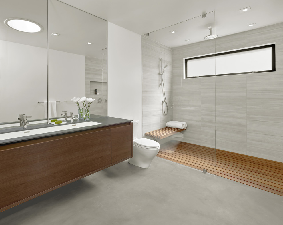 Свежая идея для дизайна: главная ванная комната среднего размера в стиле модернизм с плоскими фасадами, темными деревянными фасадами, душем без бортиков, унитазом-моноблоком, серой плиткой, белыми стенами, бетонным полом и врезной раковиной - отличное фото интерьера