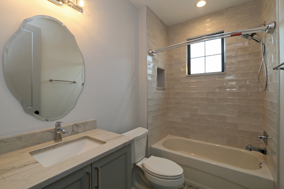 This is an example of a medium sized mediterranean family bathroom in Orlando with recessed-panel cabinets, grey cabinets, an alcove bath, an alcove shower, a one-piece toilet, white tiles, glass tiles, grey walls, a submerged sink, quartz worktops, grey floors, a shower curtain, multi-coloured worktops, a single sink and a built in vanity unit.