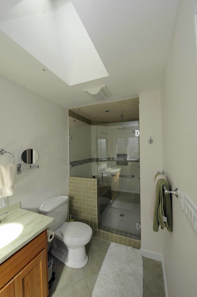Double shower - transitional green tile and ceramic tile double shower idea in San Francisco with an integrated sink, flat-panel cabinets, medium tone wood cabinets, solid surface countertops and a two-piece toilet
