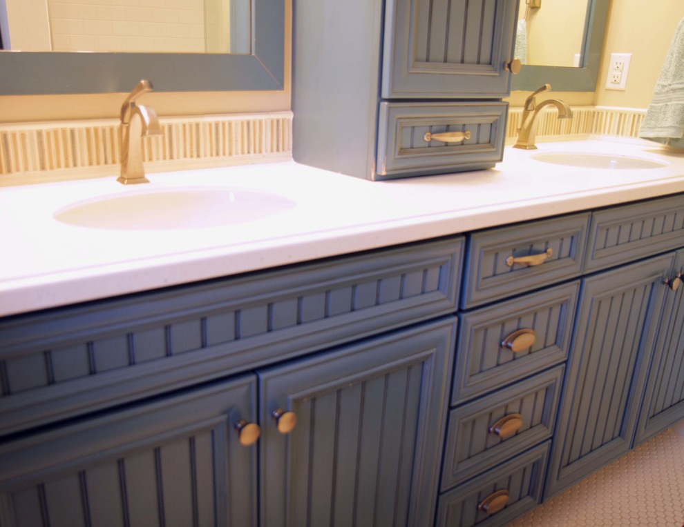 Inredning av ett klassiskt mellanstort badrum med dusch, med luckor med profilerade fronter, blå skåp, ett badkar i en alkov, en dusch/badkar-kombination, vita väggar, mosaikgolv, bänkskiva i akrylsten och vitt golv