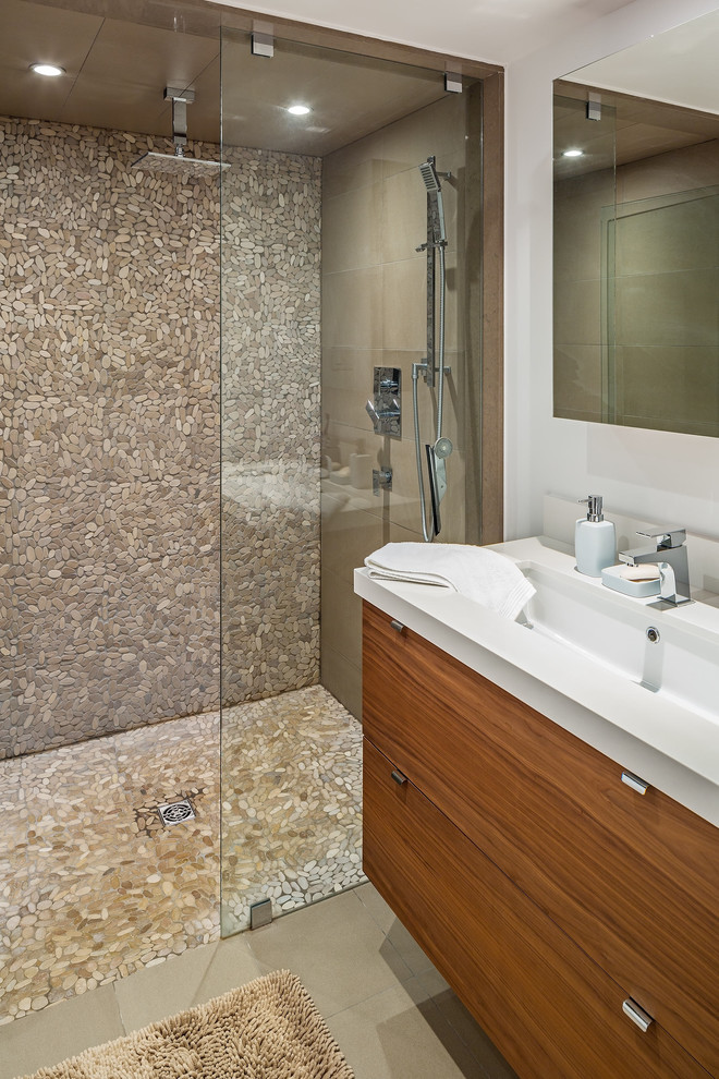 Идея дизайна: ванная комната в современном стиле с монолитной раковиной, плоскими фасадами, фасадами цвета дерева среднего тона, бежевой плиткой, галечной плиткой и полом из галечной плитки