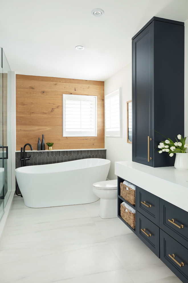 Пример оригинального дизайна: главная ванная комната в стиле неоклассика (современная классика) с фасадами с утопленной филенкой, синими фасадами, отдельно стоящей ванной, белыми стенами и белой столешницей