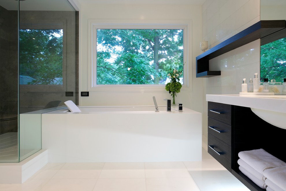 Inspiration for a mid-sized contemporary master porcelain tile and white tile porcelain tile alcove shower remodel in Toronto with flat-panel cabinets, dark wood cabinets, an undermount tub, a two-piece toilet, white walls, an undermount sink and solid surface countertops