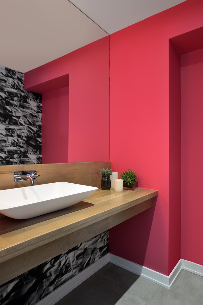 Modernes Duschbad mit Aufsatzwaschbecken, Waschtisch aus Holz, Toilette mit Aufsatzspülkasten, roter Wandfarbe, Betonboden und brauner Waschtischplatte in Toronto
