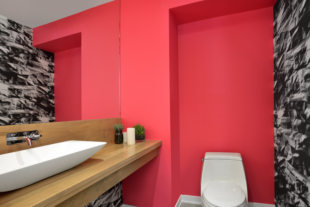 Diseño de cuarto de baño actual con sanitario de una pieza, paredes rojas, aseo y ducha, lavabo sobreencimera, encimera de madera y suelo de cemento