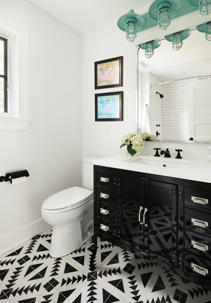 Immagine di una stanza da bagno con doccia classica di medie dimensioni con ante nere, WC a due pezzi, pareti bianche, pavimento in cementine, top in superficie solida e lavabo sottopiano