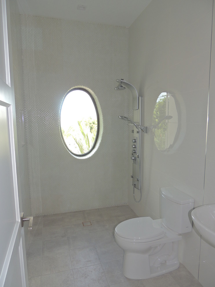 Example of a mid-sized minimalist 3/4 white tile and porcelain tile porcelain tile doorless shower design in Miami with a one-piece toilet, a wall-mount sink and white walls