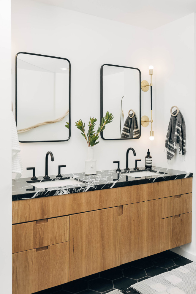 Cette image montre une grande salle de bain principale design en bois brun avec un placard à porte plane, un mur blanc, carreaux de ciment au sol, un lavabo encastré, un plan de toilette en marbre, un sol noir, un plan de toilette noir, meuble double vasque et meuble-lavabo suspendu.