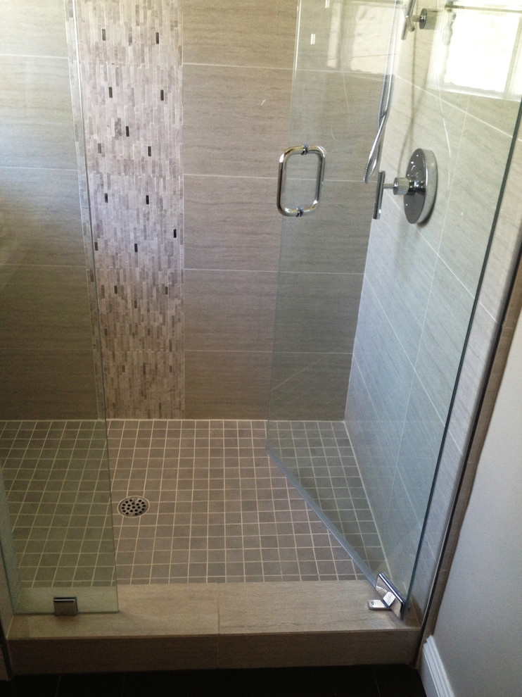 Cette image montre une salle de bain design avec une douche d'angle, un carrelage gris, des dalles de pierre et un mur beige.