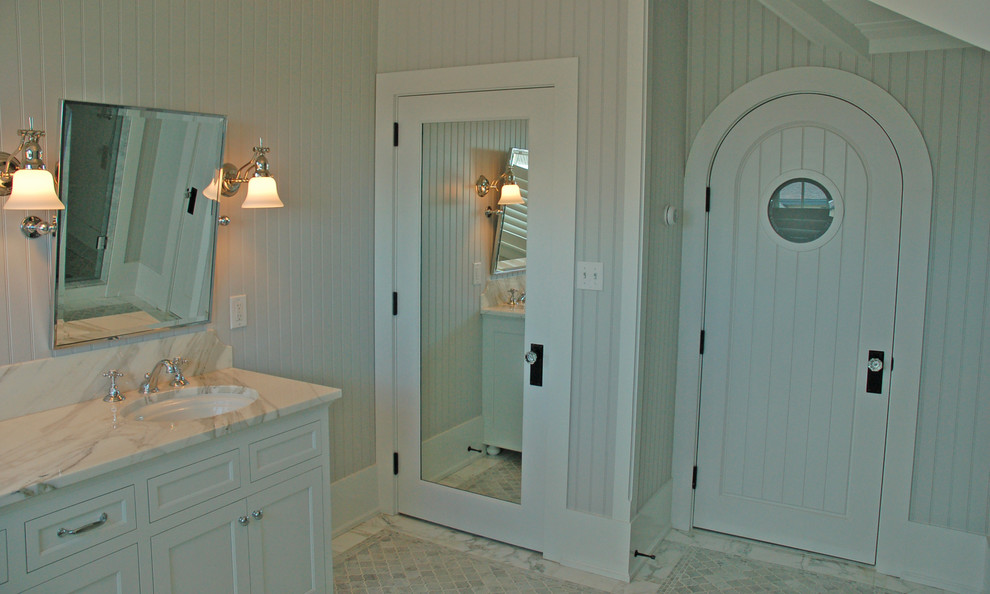 На фото: главная ванная комната в морском стиле с фасадами в стиле шейкер, белыми фасадами, белыми стенами, мраморным полом, врезной раковиной, мраморной столешницей и белым полом с